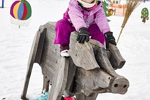 Zona de prácticas de Hexenwiese en el valle de SkiWelt Söll Niño sobre un cerdo de madera en un parque infantil de nieve