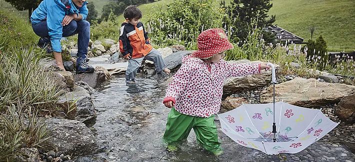 Hexenwasser Hochsöll i dårligt vejr i regnen med paraply Børneprogram på bjerget i SkiWelt Wilder Kaiser Brixental